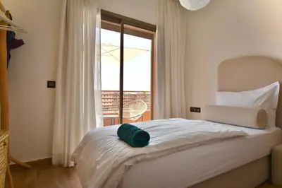 a bedroom with a bed with a view of a balcony at Superbe appart cosy avec piscine in Marrakech