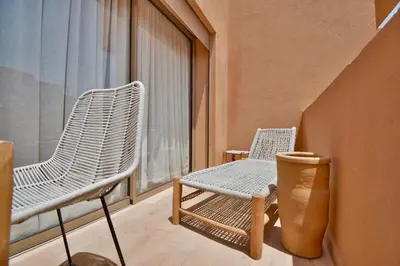 two chairs sitting on a balcony with a window at Superbe appart cosy avec piscine in Marrakech