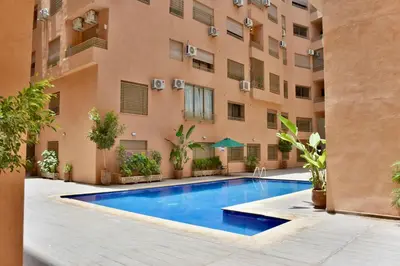 an apartment courtyard with a swimming pool in front of a building at Superbe appart cosy avec piscine in Marrakech
