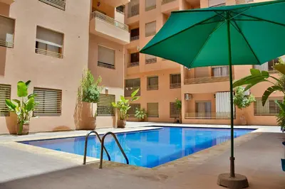 an umbrella next to a swimming pool in a building at Superbe appart cosy avec piscine in Marrakech