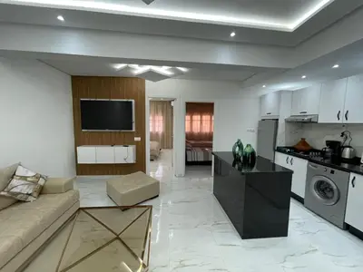 a kitchen and living room with a couch and a tv at Joli appartement hyper centre Guéliz in Marrakech