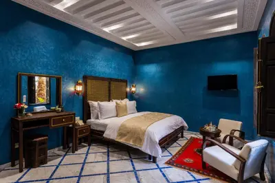 a bedroom with blue walls and a bed and a mirror at Alrashid Marrakech Boutique Hotel & SPA in Marrakech