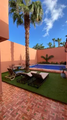 a palm tree and lounge chairs next to a pool at Villa Lyazidi in Marrakech