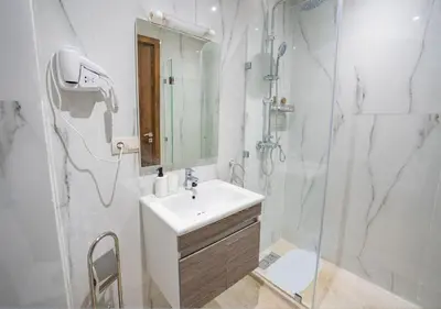 a white bathroom with a sink and a shower at Appart Mayar 52 in Marrakech