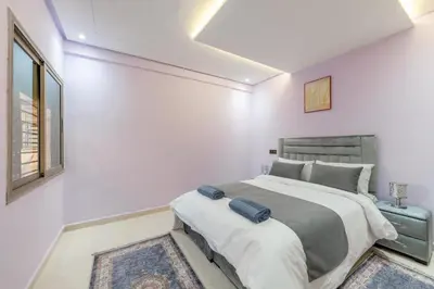 a white bedroom with a large bed and a window at Cozy appartement à Gueliz juste les familles in Marrakech