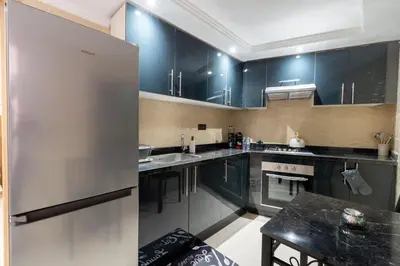 a kitchen with black cabinets and a stainless steel refrigerator at Cozy appartement à Gueliz juste les familles in Marrakech