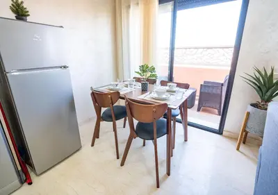 a dining room with a table and a refrigerator at Appart Mayar 58 in Marrakech