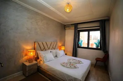 a bedroom with a bed with two lamps and a window at La Nina Appartement Marrakech in Marrakech