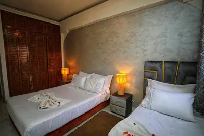 two beds in a hotel room with two lamps at La Nina Appartement Marrakech in Marrakech