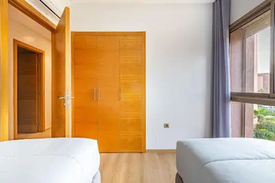 a bedroom with two beds and a wooden door at New! Résidence de Luxe avec Piscine & parking in Marrakech