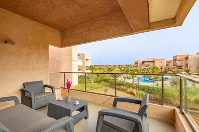 a room with a balcony with chairs and a table at New! Résidence de Luxe avec Piscine & parking in Marrakech