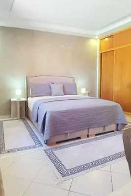 a bedroom with a bed with purple sheets and two rugs at Family House Marrakech in Marrakech