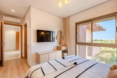 a bedroom with a large bed and a window at New! App Spacieux avec Piscine et Parking à Saphir in Marrakech