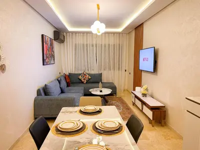 a living room with a table and a couch at Bel appartement haut standing in Marrakech