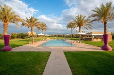 a swimming pool with palm trees and a house at Villa des stars in Marrakech