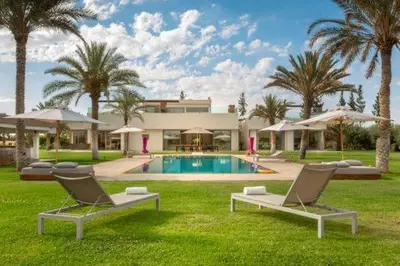 a house with a swimming pool and two lounge chairs at Villa des stars in Marrakech