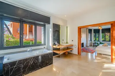 a bathroom with a bath tub and a bedroom at Villa Dar Chama ,piscine privée , Au cœur de Marrakech in Marrakech