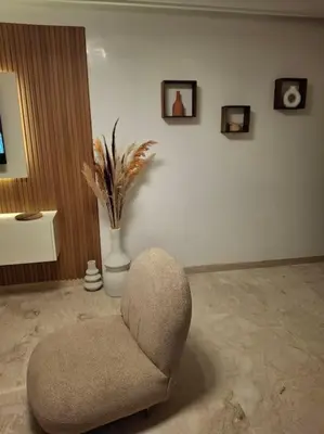 a living room with a chair and a vase with pictures at Hypercentre, Cosy, 2 piscines, Sauna, Hammam in Marrakech
