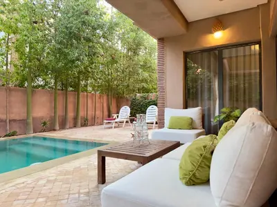 a patio with a couch and a table next to a pool at Villa Atlas view in Marrakech