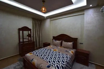 a bedroom with a bed and a mirror at Appartement familial proche aéroport et Oasiria in Marrakech