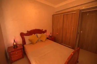 a bedroom with a bed with a wooden headboard at Appartement familial proche aéroport et Oasiria in Marrakech