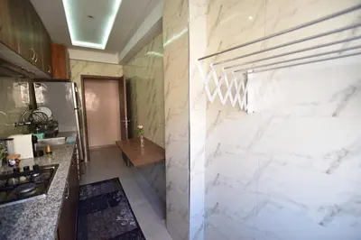 a kitchen with white marble walls and a refrigerator at Appartement familial proche aéroport et Oasiria in Marrakech