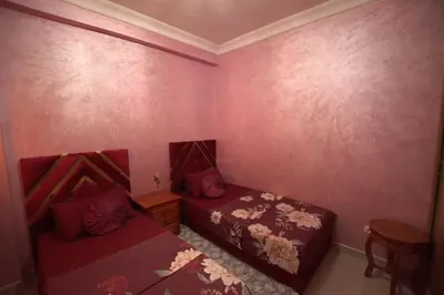 a bedroom with two beds and pink walls at Appartement familial proche aéroport et Oasiria in Marrakech