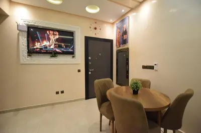 a dining room with a table and a tv on the wall at Appartement familial proche aéroport et Oasiria in Marrakech