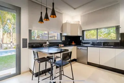 a kitchen with a black counter top and some windows at Exotic villa-VIP-family only -housekeeper ,Billard,ping-pong,piscine privée chauffée-sur demande- in Marrakech