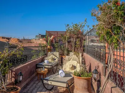 a patio with two tables and trees and a fence at Riad Irhalne in Marrakech