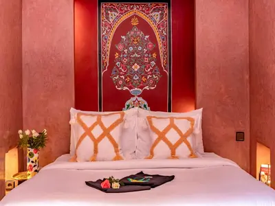 a bedroom with a bed with a red wall at Riad Irhalne in Marrakech