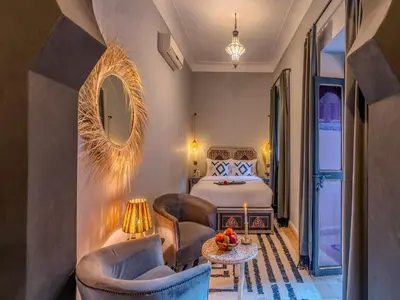 a bedroom with a bed and two chairs and a table at Riad Irhalne in Marrakech