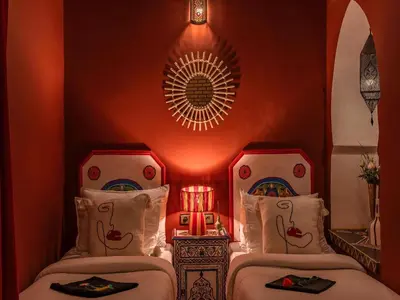 two beds in a room with a red wall at Riad Irhalne in Marrakech