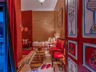 a red living room with a red chair and a table at Riad Irhalne in Marrakech
