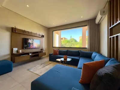 a living room with a blue couch and a tv at Villa Oasis in Marrakech