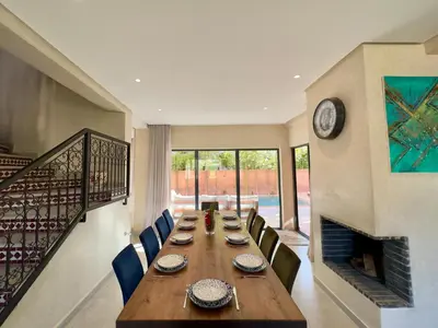 a dining room with a long table and a fireplace at Villa Oasis in Marrakech