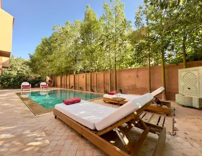 a swimming pool with a bed and a table next to a swimming pool at Villa Oasis in Marrakech