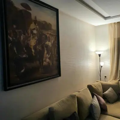 a living room with a couch and a painting on the wall at Appartement près du hôtel IBIS et WAZO et Marjane Mall in Marrakech