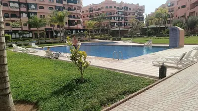 a woman standing next to a swimming pool in a building at premium village M355 in Marrakech