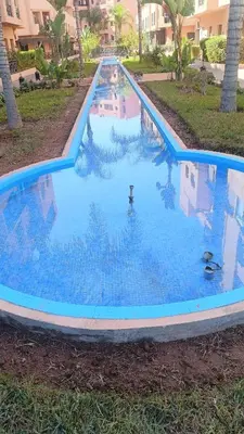 a large pool with blue water in a yard at premium village M355 in Marrakech
