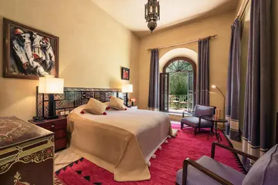 a bedroom with a bed and a chair and a window at Dar Zemora in Marrakech