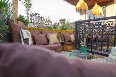 a patio with couches and a fence with plants at Riad Lulua Exclusif 3 Chambres et Piscine Rooftop in Marrakech