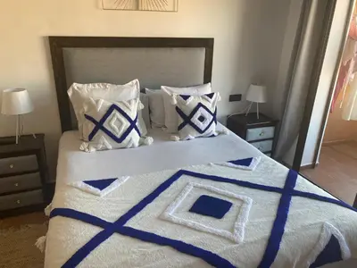 a bedroom with a large bed with blue and white pillows at Appartement luxueux 38 nour 5 in Marrakech