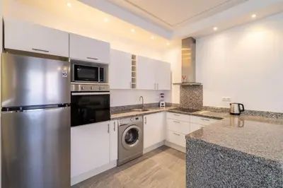 a kitchen with white cabinets and a stainless steel refrigerator at appartement hyper centre in Marrakech