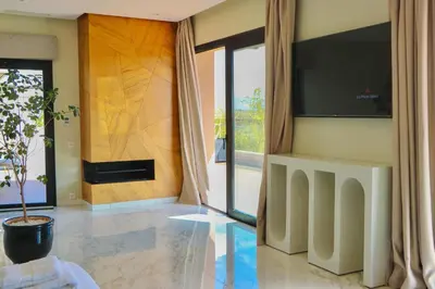 a living room with a television and a potted plant at Villa SELINA Luxury -5 suites , Piscine privée chauffée, sans vis à vis, calme & sureté - Padle , Family only in Marrakech