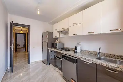 a kitchen with white cabinets and stainless steel appliances at New! App Émeraude Confort avec piscine & parking in Marrakech