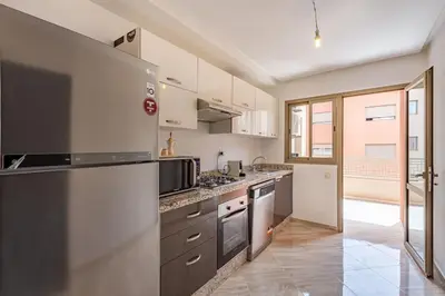 a kitchen with stainless steel appliances and a large window at New! App Émeraude Confort avec piscine & parking in Marrakech