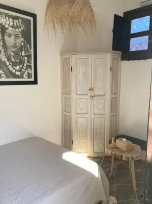 a bedroom with a bed and a cabinet with a picture at Riad Cosy in Marrakech