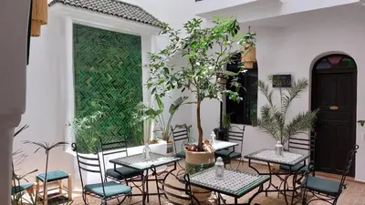 a patio with tables and chairs and plants at Riad Cosy in Marrakech