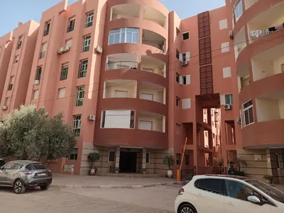 a pink building with cars parked in front of it at Appartement Marrakech Avec Piscine in Marrakech